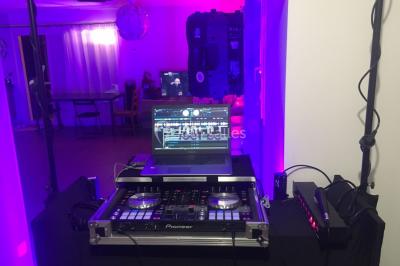 Poste de DJ éclairé par des lumières violettes, entouré de décorations d'Halloween et de toiles d'araignée.