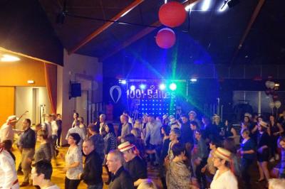 Un DJ mixe derrière une table éclairée de lumières LED violettes, avec un mur décoratif en arrière-plan.