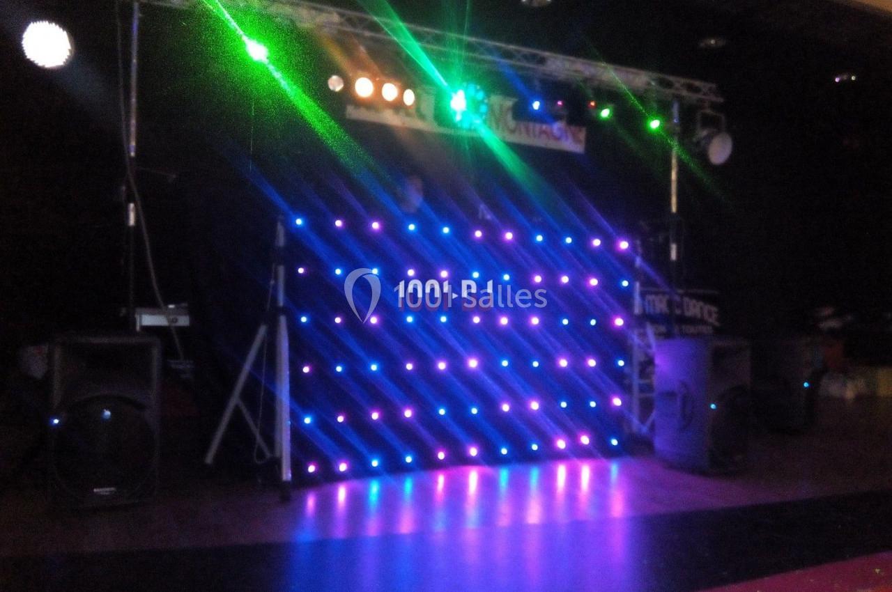 Pupitre de DJ illuminé par des lumières LED colorées, entouré d'équipements audio dans une salle sombre.