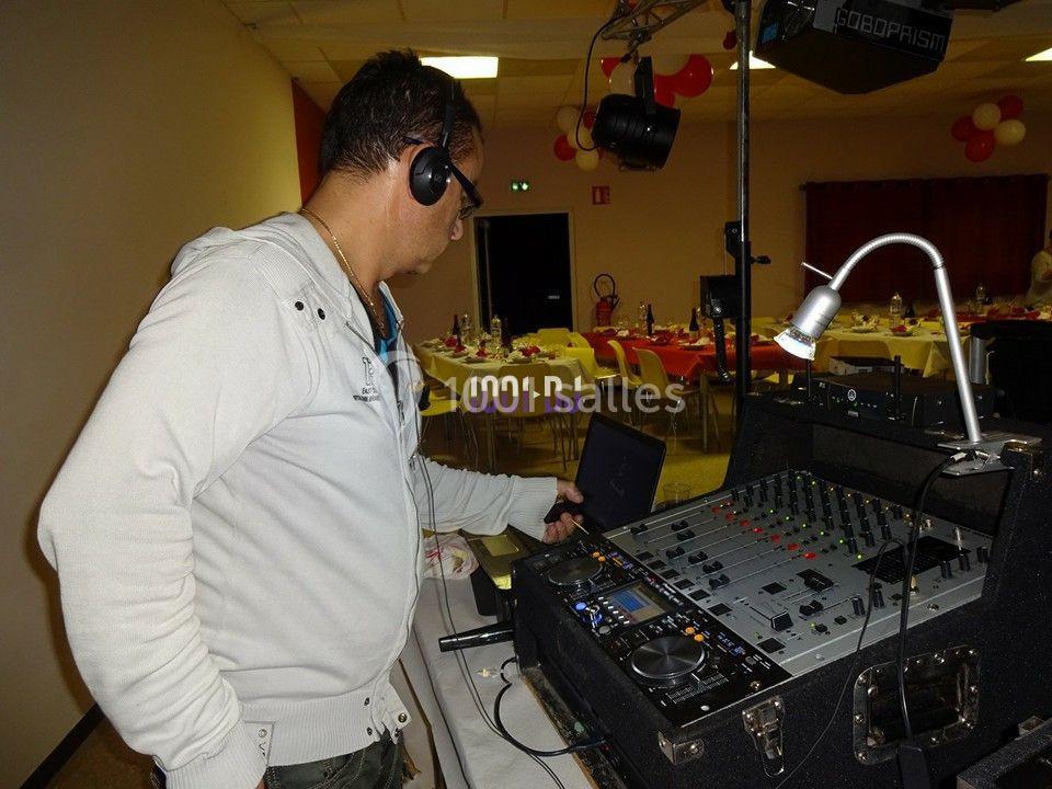 Un DJ avec un casque ajuste une table de mixage dans une salle décorée pour un événement.