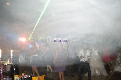 Un DJ mixe derrière une table éclairée de lumières LED violettes, avec un mur décoratif en arrière-plan.