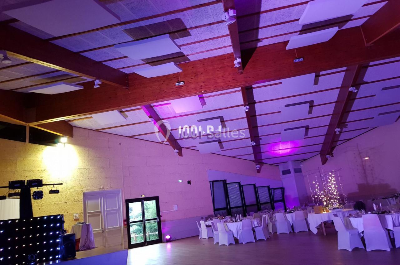 Salle de réception avec tables dressées, éclairage tamisé et décorations lumineuses au plafond.