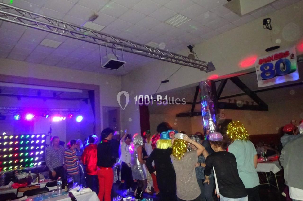 Des personnes dansent et s'amusent lors d'une soirée festive avec éclairages colorés et décorations rétro.