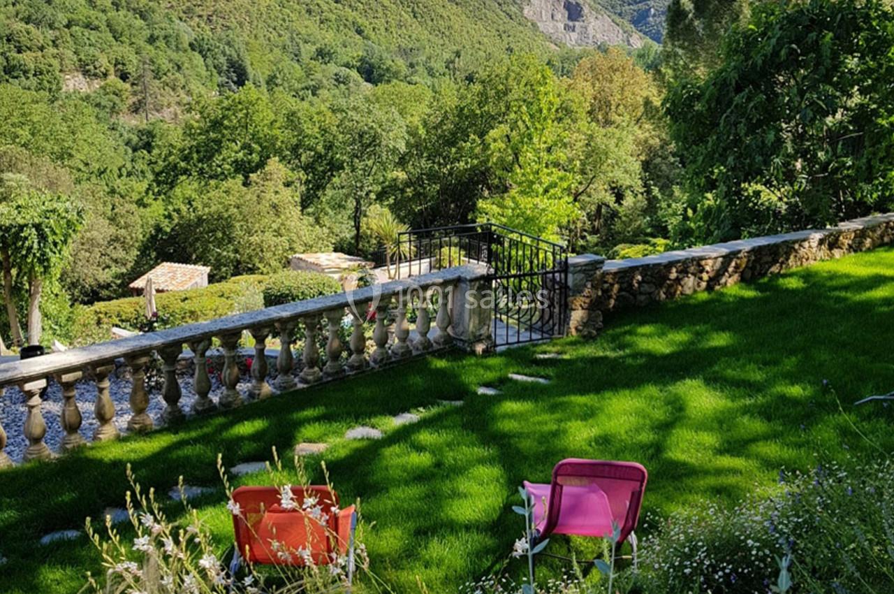 Deux chaises colorées sur une pelouse verdoyante, avec vue sur un paysage vallonné et arboré.