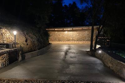 Allée en béton fraîchement coulée, éclairée par des lampadaires, entourée d'arbres et de végétation la nuit.