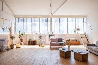 Salle de bain lumineuse avec baignoire blanche, mur rose, plante en pot et vue sur un escalier en bois.