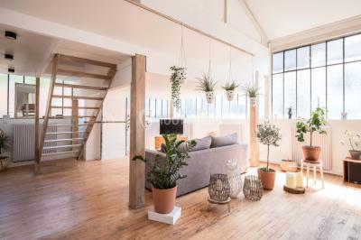 Salle de bain lumineuse avec baignoire blanche, mur rose, plante en pot et vue sur un escalier en bois.