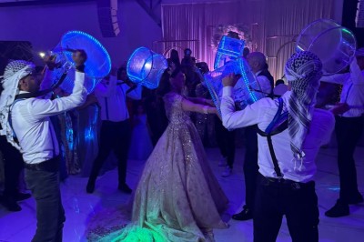 Un groupe de personnes en tenue traditionnelle célèbre un événement sous des lustres dans une grande salle éclairée.