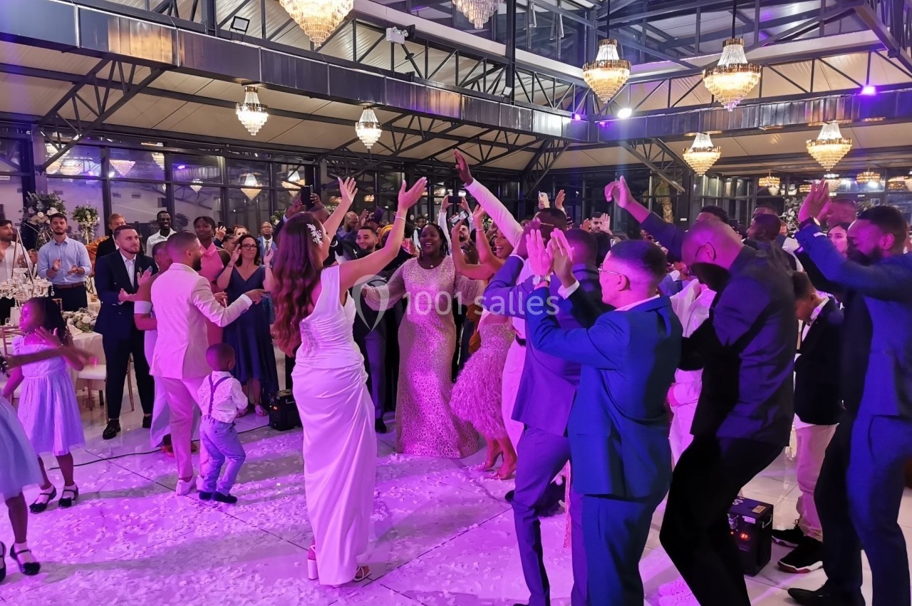 Groupe de personnes dansant sous des lumières violettes dans une salle de réception avec des lustres suspendus.
