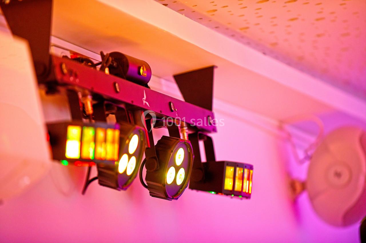 Projecteurs LED suspendus émettant des lumières colorées dans une pièce à l'éclairage tamisé.