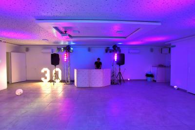 Projecteurs LED rouges fixés sur une barre métallique, éclairant un mur avec des reflets lumineux violets.