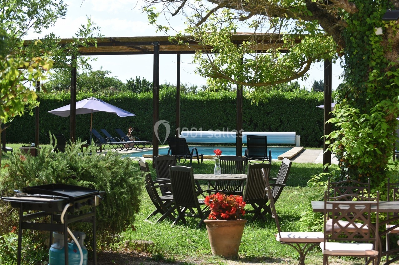 Mobilier de jardin en bois autour d'une table, près d'une piscine entourée de transats et de parasols dans un jardin…