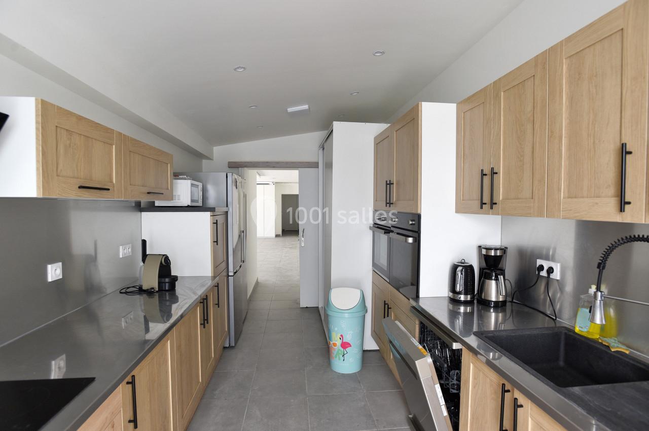 Cuisine moderne avec meubles en bois clair, plan de travail gris, électroménagers intégrés et évier noir.