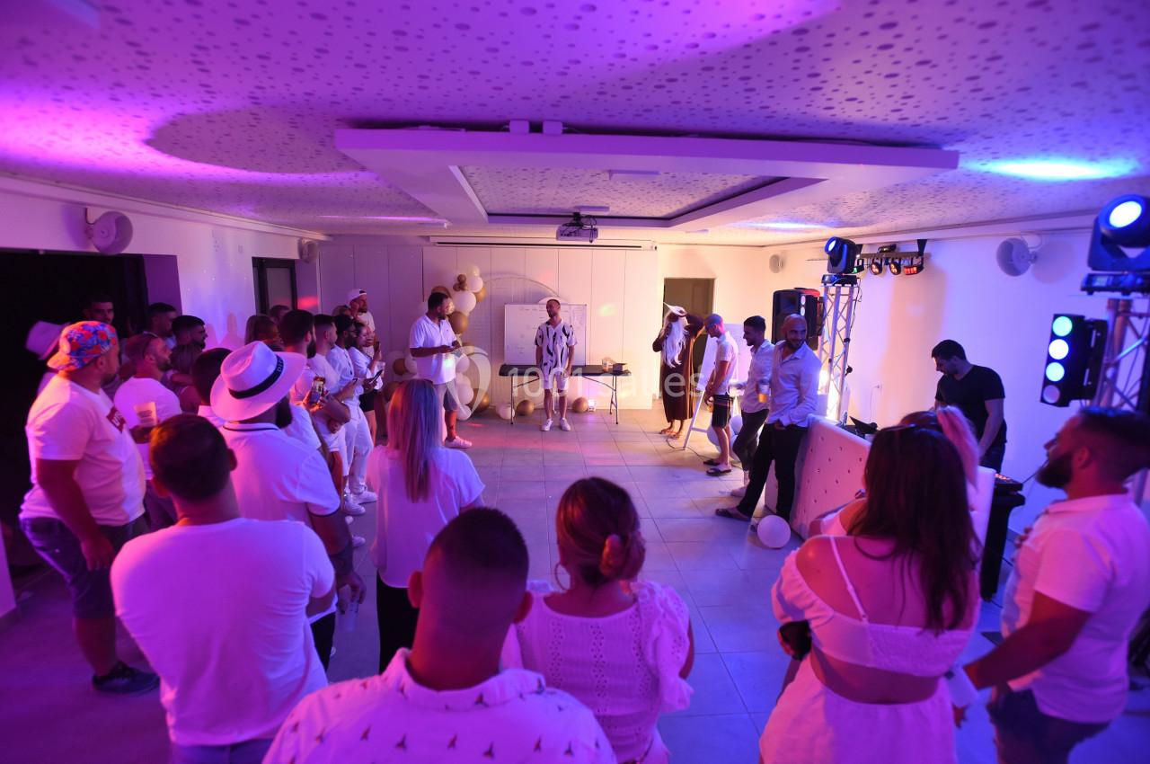 Groupe de personnes rassemblées dans une salle éclairée par des lumières colorées, participant à un événement festif.