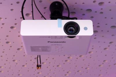 Salle de bain moderne avec carrelage gris, meuble suspendu, miroir, petite fenêtre et poubelle blanche au sol.