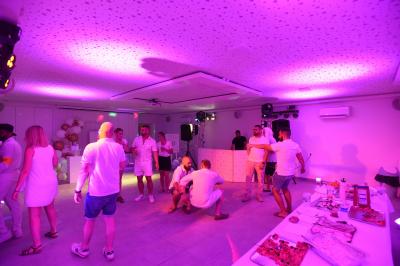 Salle de bain moderne avec carrelage gris, meuble suspendu, miroir, petite fenêtre et poubelle blanche au sol.
