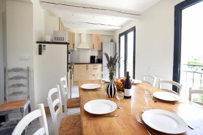 Salle de bain moderne avec carrelage gris, meuble suspendu, miroir, petite fenêtre et poubelle blanche au sol.