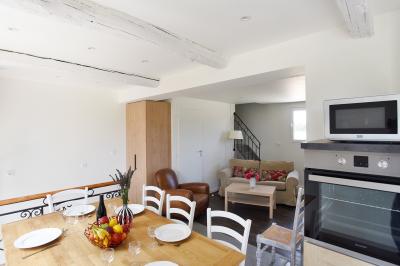 Salle de bain moderne avec carrelage gris, meuble suspendu, miroir, petite fenêtre et poubelle blanche au sol.