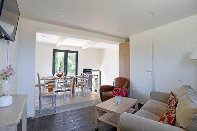 Salle de bain moderne avec carrelage gris, meuble suspendu, miroir, petite fenêtre et poubelle blanche au sol.