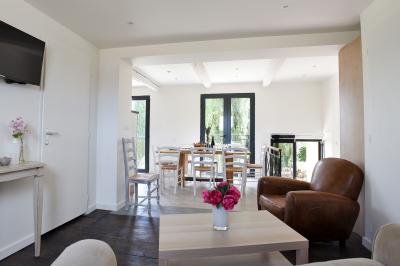 Salle de bain moderne avec carrelage gris, meuble suspendu, miroir, petite fenêtre et poubelle blanche au sol.