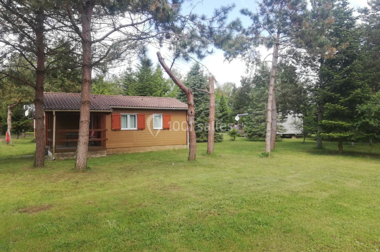 Chalet en bois entouré de pelouse et d'arbres dans un environnement naturel.