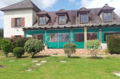 Des personnes assises en extérieur assistent à une cérémonie devant des tables décorées, près de chalets en bois.