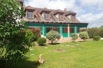 Des personnes assises en extérieur assistent à une cérémonie devant des tables décorées, près de chalets en bois.