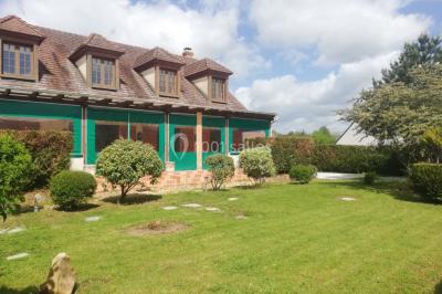 Des personnes assises en extérieur assistent à une cérémonie devant des tables décorées, près de chalets en bois.