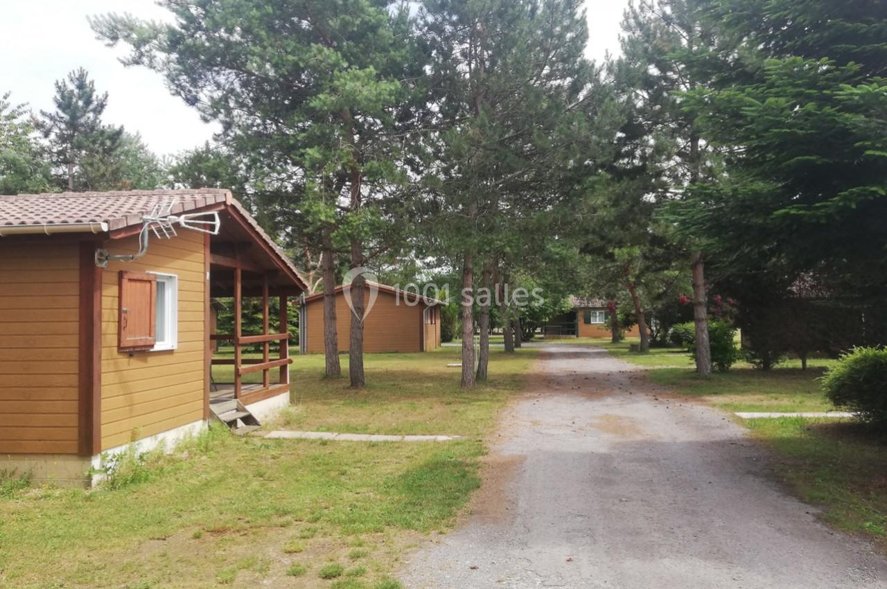 Allée bordée de chalets en bois entourés d'arbres et de pelouses dans un cadre naturel.