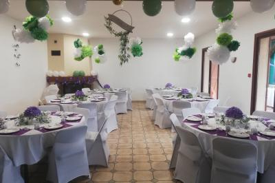 Des personnes assises en extérieur assistent à une cérémonie devant des tables décorées, près de chalets en bois.