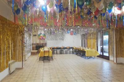 Des personnes assises en extérieur assistent à une cérémonie devant des tables décorées, près de chalets en bois.