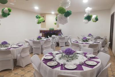 Des personnes assises en extérieur assistent à une cérémonie devant des tables décorées, près de chalets en bois.