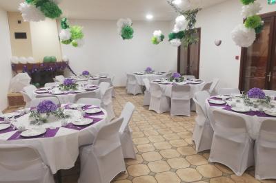 Des personnes assises en extérieur assistent à une cérémonie devant des tables décorées, près de chalets en bois.