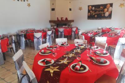 Des personnes assises en extérieur assistent à une cérémonie devant des tables décorées, près de chalets en bois.