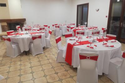 Des personnes assises en extérieur assistent à une cérémonie devant des tables décorées, près de chalets en bois.