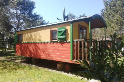 Des personnes assises en extérieur assistent à une cérémonie devant des tables décorées, près de chalets en bois.