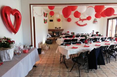 Des personnes assises en extérieur assistent à une cérémonie devant des tables décorées, près de chalets en bois.