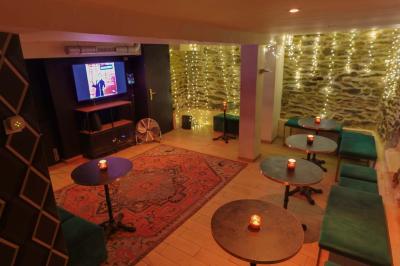 Intérieur d'un bar chaleureux avec tables rondes, bougies, grand miroir, comptoir en bois et menu affiché au mur.