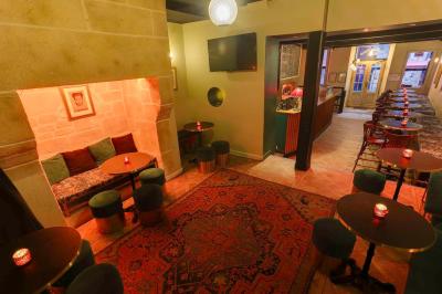 Intérieur d'un bar chaleureux avec tables rondes, bougies, grand miroir, comptoir en bois et menu affiché au mur.