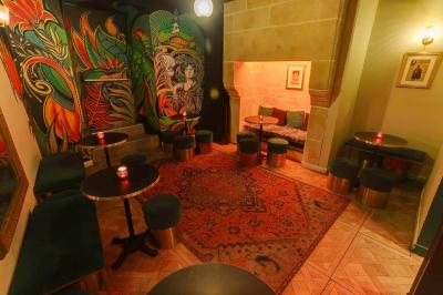 Intérieur d'un bar chaleureux avec tables rondes, bougies, grand miroir, comptoir en bois et menu affiché au mur.