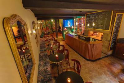Intérieur d'un bar chaleureux avec tables rondes, bougies, grand miroir, comptoir en bois et menu affiché au mur.