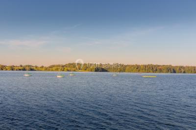 Groupe de personnes rassemblées devant une maison en pierre avec un chapiteau, sur une pelouse par temps ensoleillé.