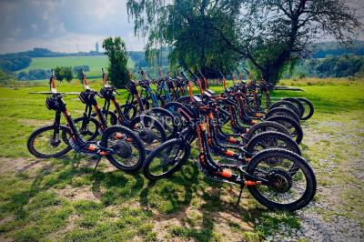 Groupe de personnes rassemblées devant une maison en pierre avec un chapiteau, sur une pelouse par temps ensoleillé.