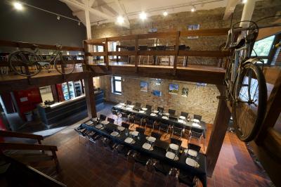 Groupe de personnes rassemblées devant une maison en pierre avec un chapiteau, sur une pelouse par temps ensoleillé.