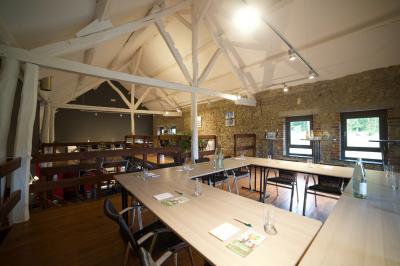 Groupe de personnes rassemblées devant une maison en pierre avec un chapiteau, sur une pelouse par temps ensoleillé.