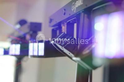 Salle sombre avec des jeux de lumières colorées, des lasers et une foule dans une ambiance festive.