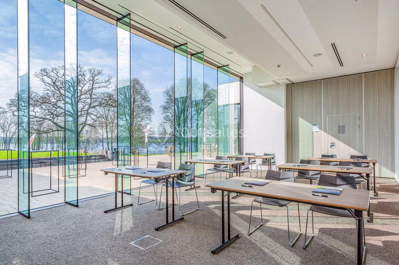 Salle de réunion lumineuse avec grandes baies vitrées donnant sur un espace extérieur arboré.