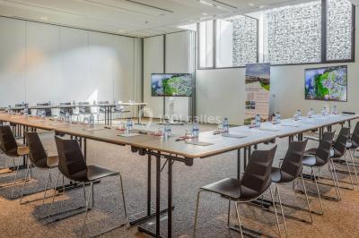 Terrasse en bois avec table et chaises, vue sur un jardin verdoyant et un lac au coucher du soleil.