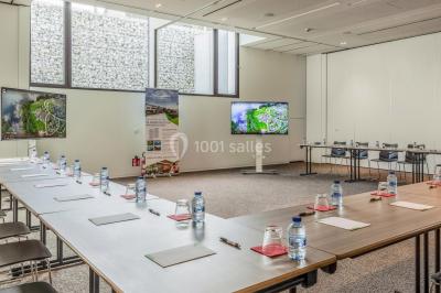 Terrasse en bois avec table et chaises, vue sur un jardin verdoyant et un lac au coucher du soleil.