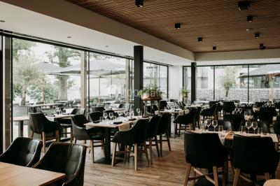 Terrasse en bois avec table et chaises, vue sur un jardin verdoyant et un lac au coucher du soleil.